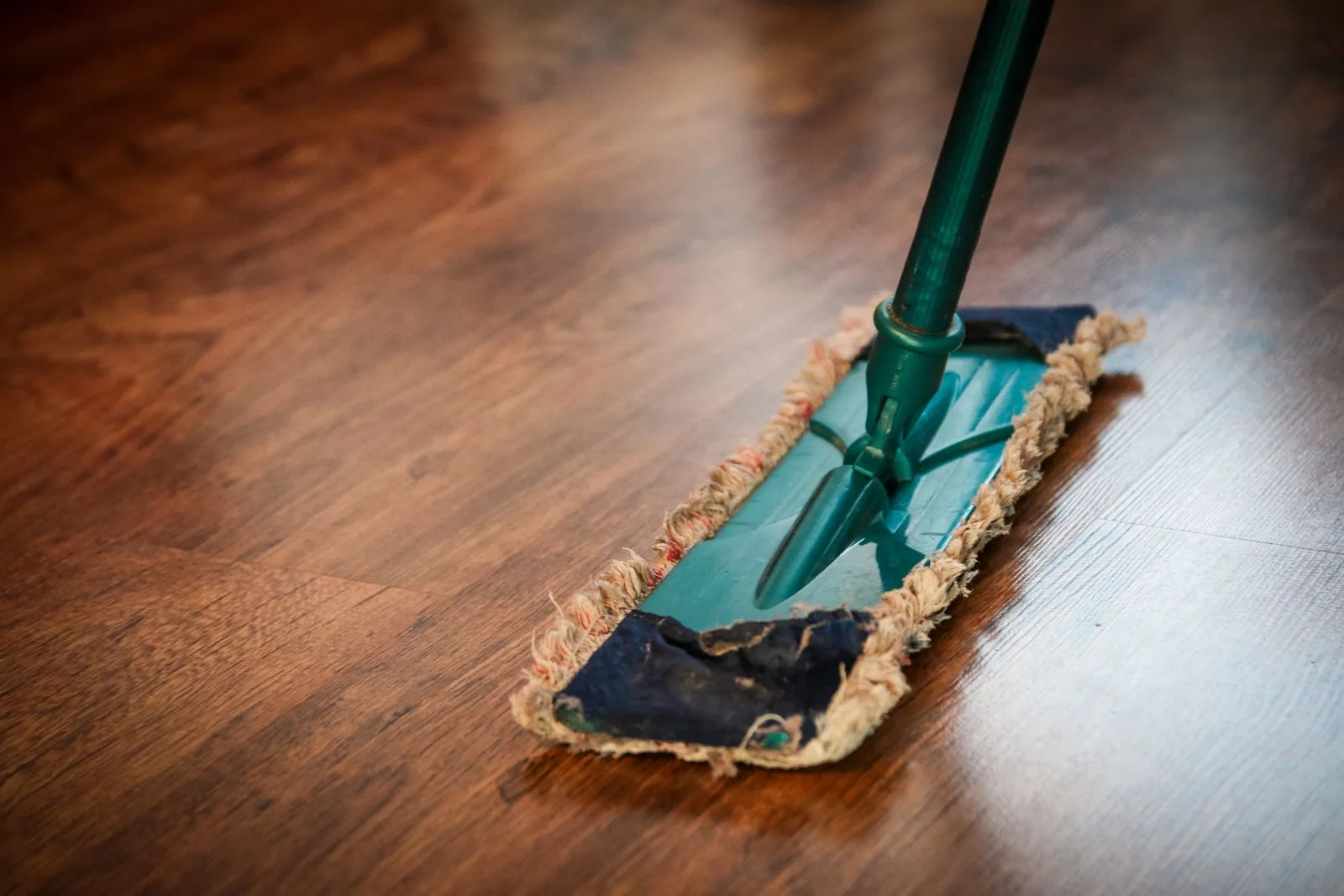 A mop passing over a dark wooden floor
