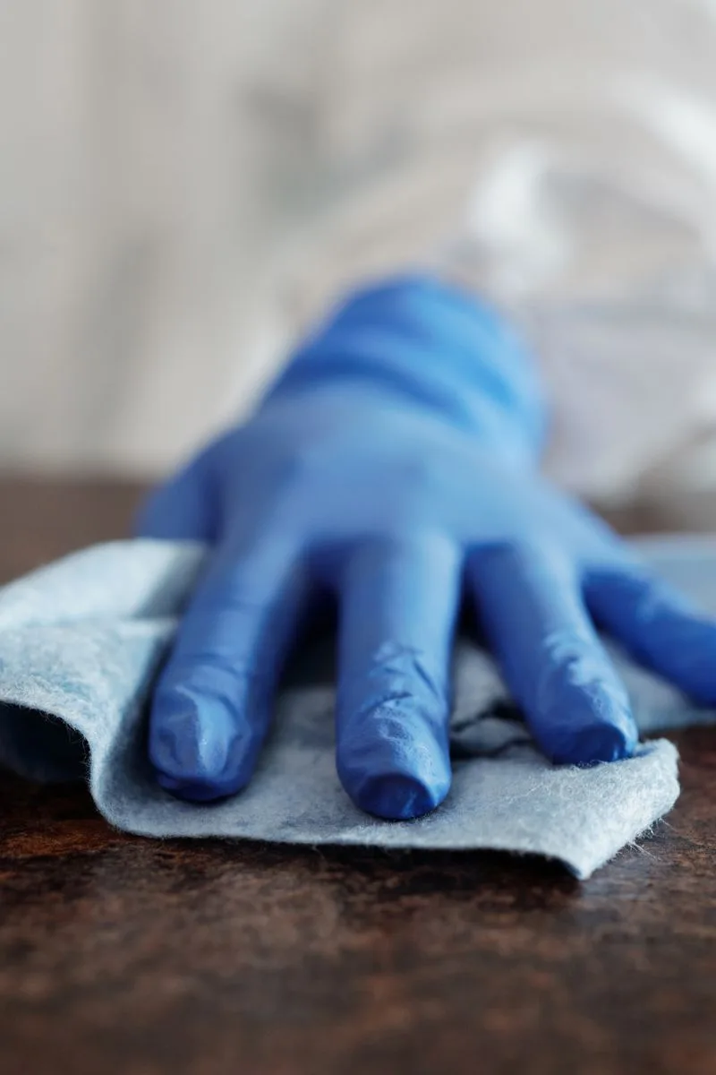 A gloved hand wiping a wooden surface